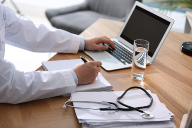 Photo of Professional doctor working on laptop in office, closeup