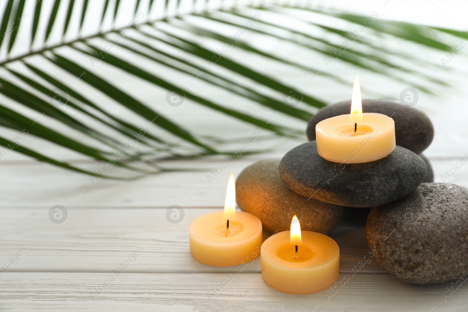 Photo of Composition with spa stones and candles on white wooden background. Space for text