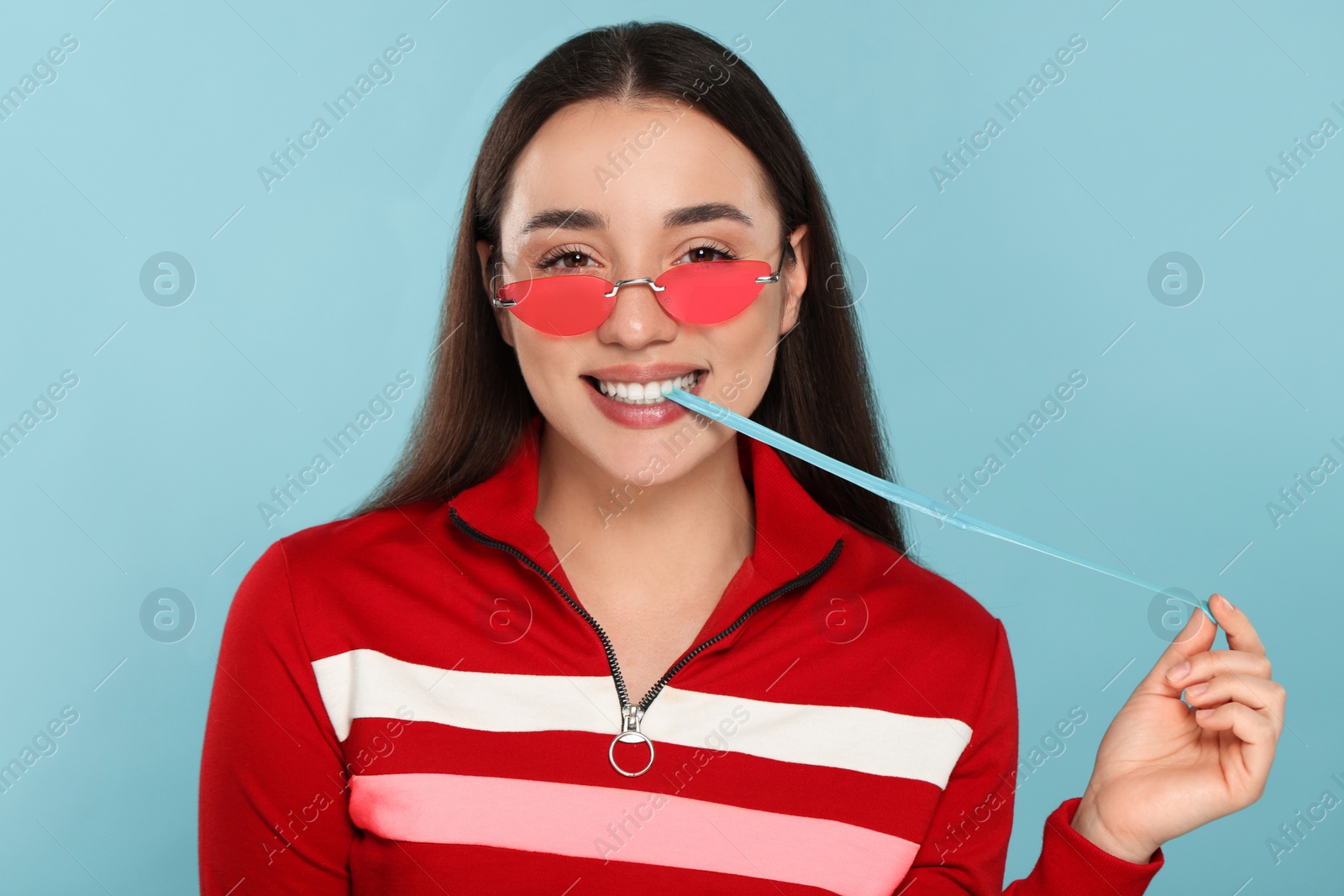 Photo of Happy young woman with bubble gum on light blue background