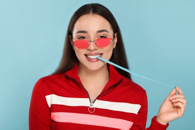 Happy young woman with bubble gum on light blue background