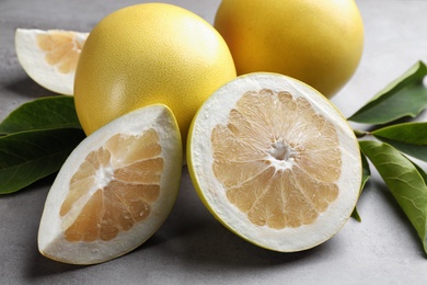 Photo of Fresh cut and whole pomelo fruits on grey table, closeup