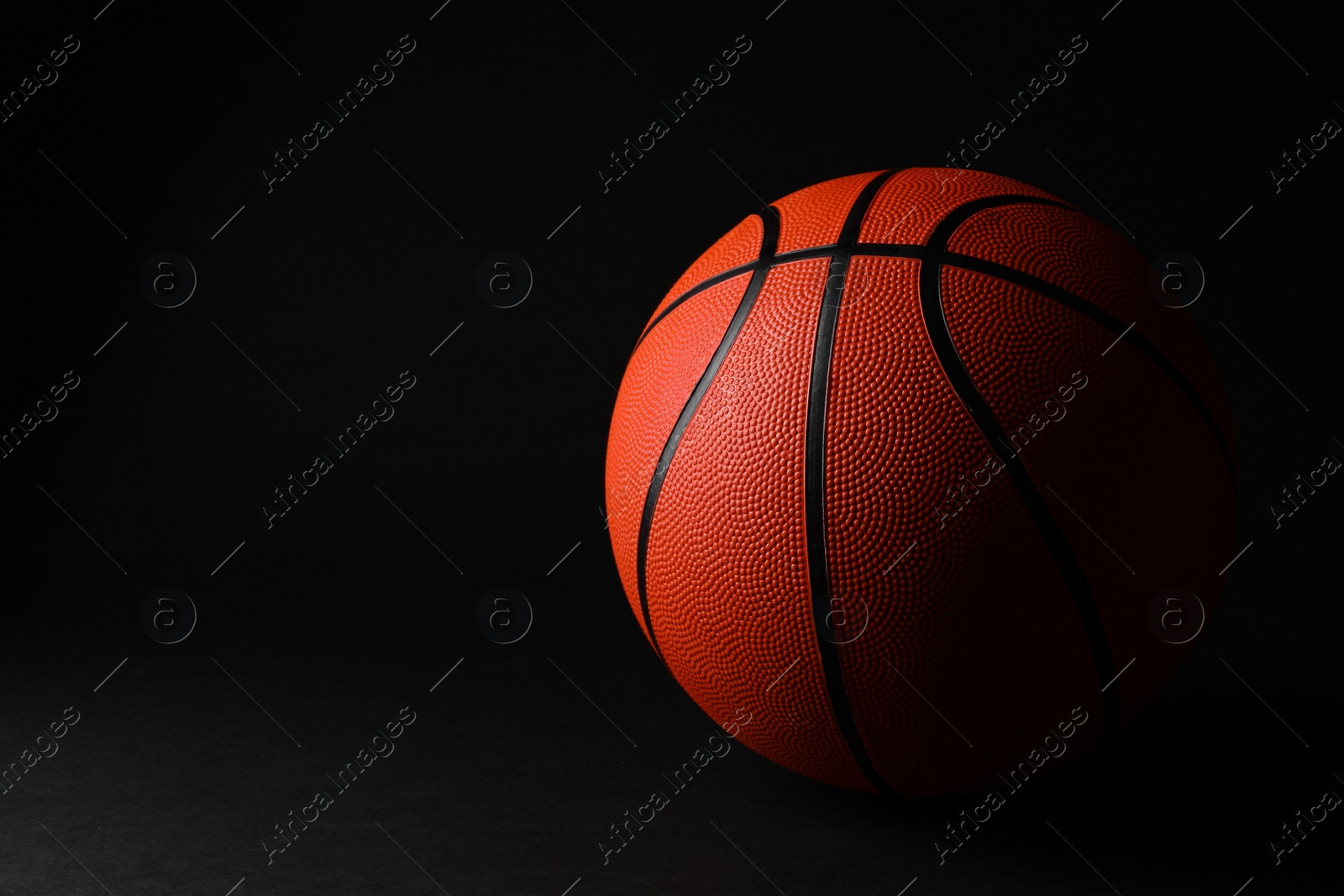 Photo of One basketball ball on black background. Space for text