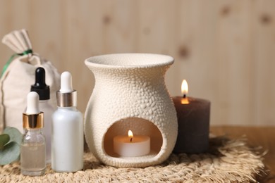 Photo of Different aromatherapy products and burning candles on table, closeup