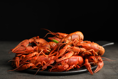 Photo of Delicious boiled crayfishes on grey table against black background