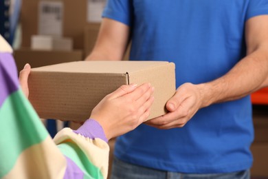 Photo of Worker giving parcel to woman at post office, closeup