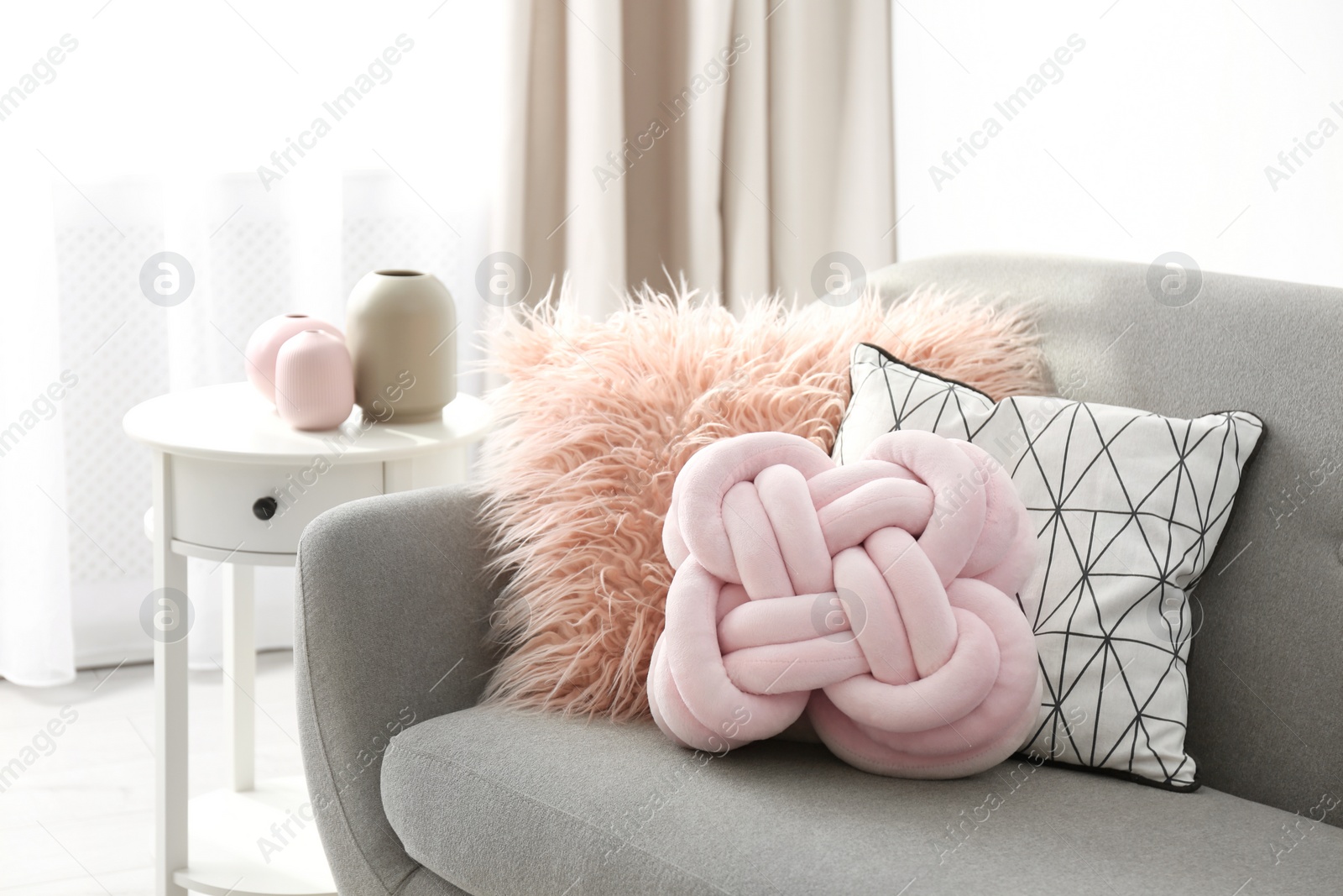 Photo of Different soft pillows on sofa in room. Interior element