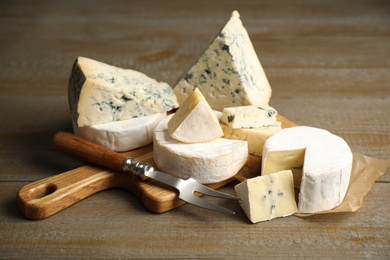 Different sorts of cheese and fork on wooden table