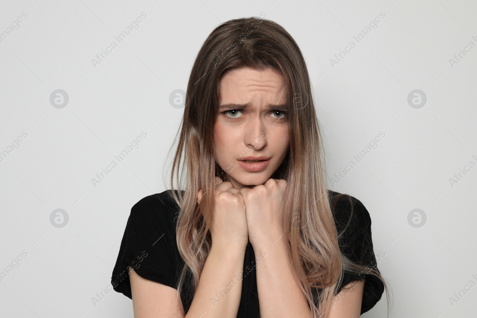 Photo of Portrait of scared woman on light background. Stop violence