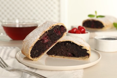 Delicious strudel with cherries and poppy seeds on white table, closeup