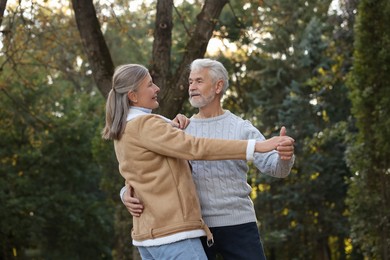 Photo of Affectionate senior couple dancing together in park. Romantic date