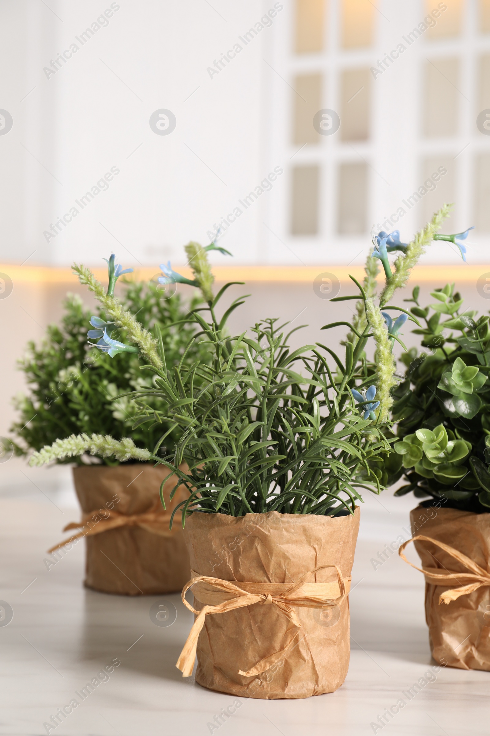 Photo of Artificial potted herbs on white marble table in kitchen. Home decor