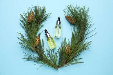 Photo of Flat lay composition with essential oil, pine branches and cones on light blue background