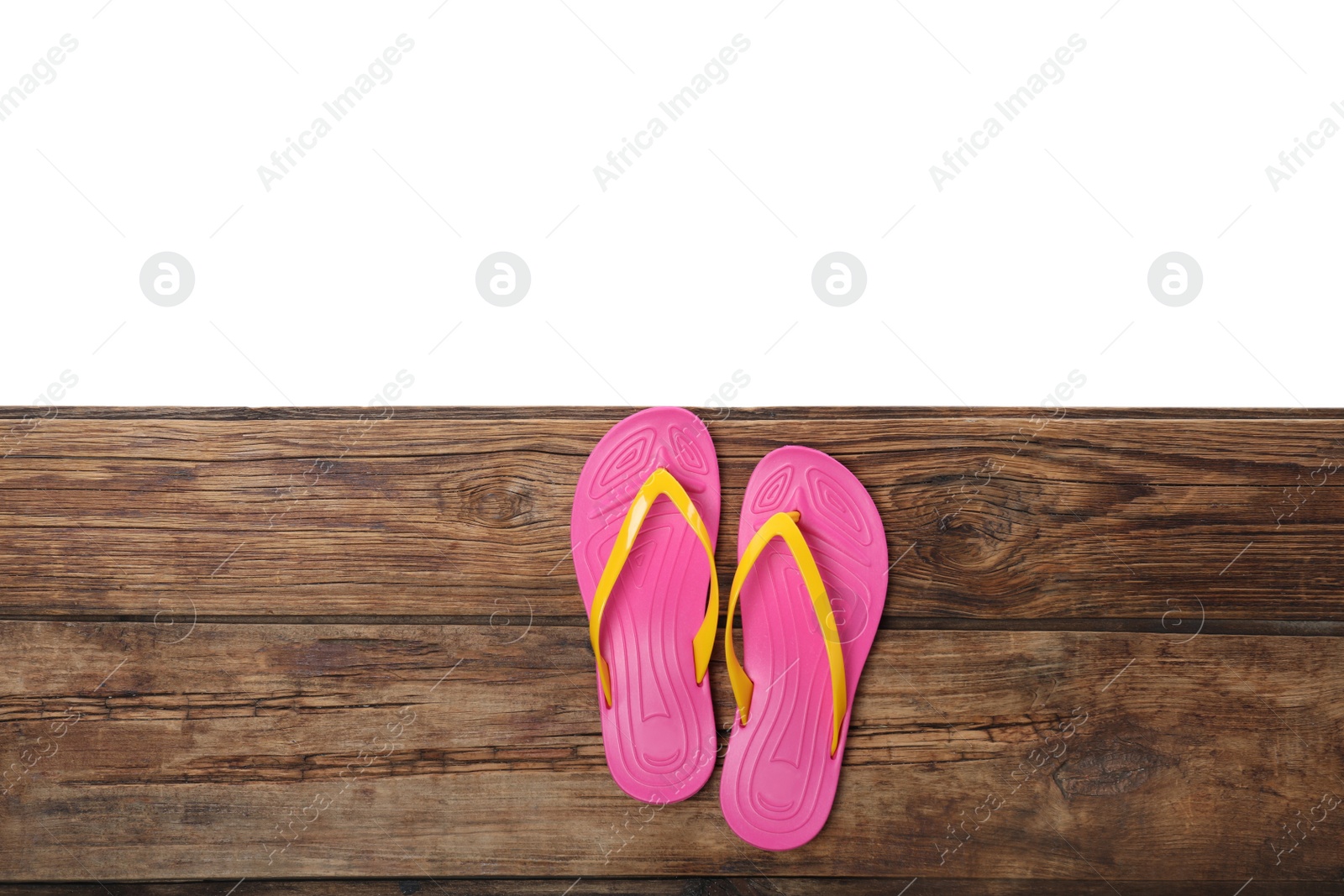 Photo of Pink flip flops on wooden table against white background, top view