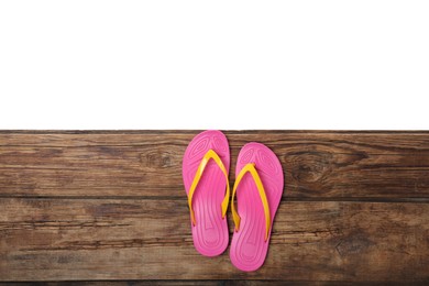 Pink flip flops on wooden table against white background, top view