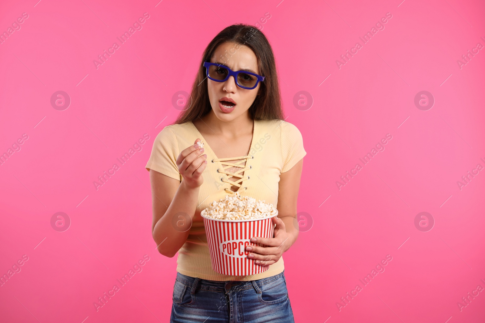 Photo of Emotional woman with 3D glasses and popcorn during cinema show on color background