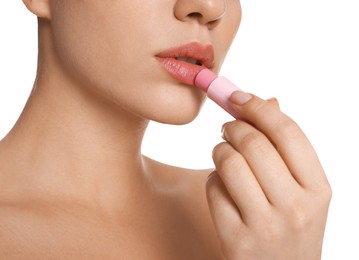 Young woman applying lip balm on white background, closeup