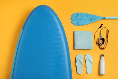 Photo of Flat lay composition with SUP board on yellow background. Water sport