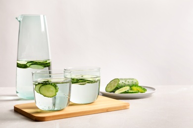 Photo of Glasses and jug of fresh cucumber water on table. Space for text