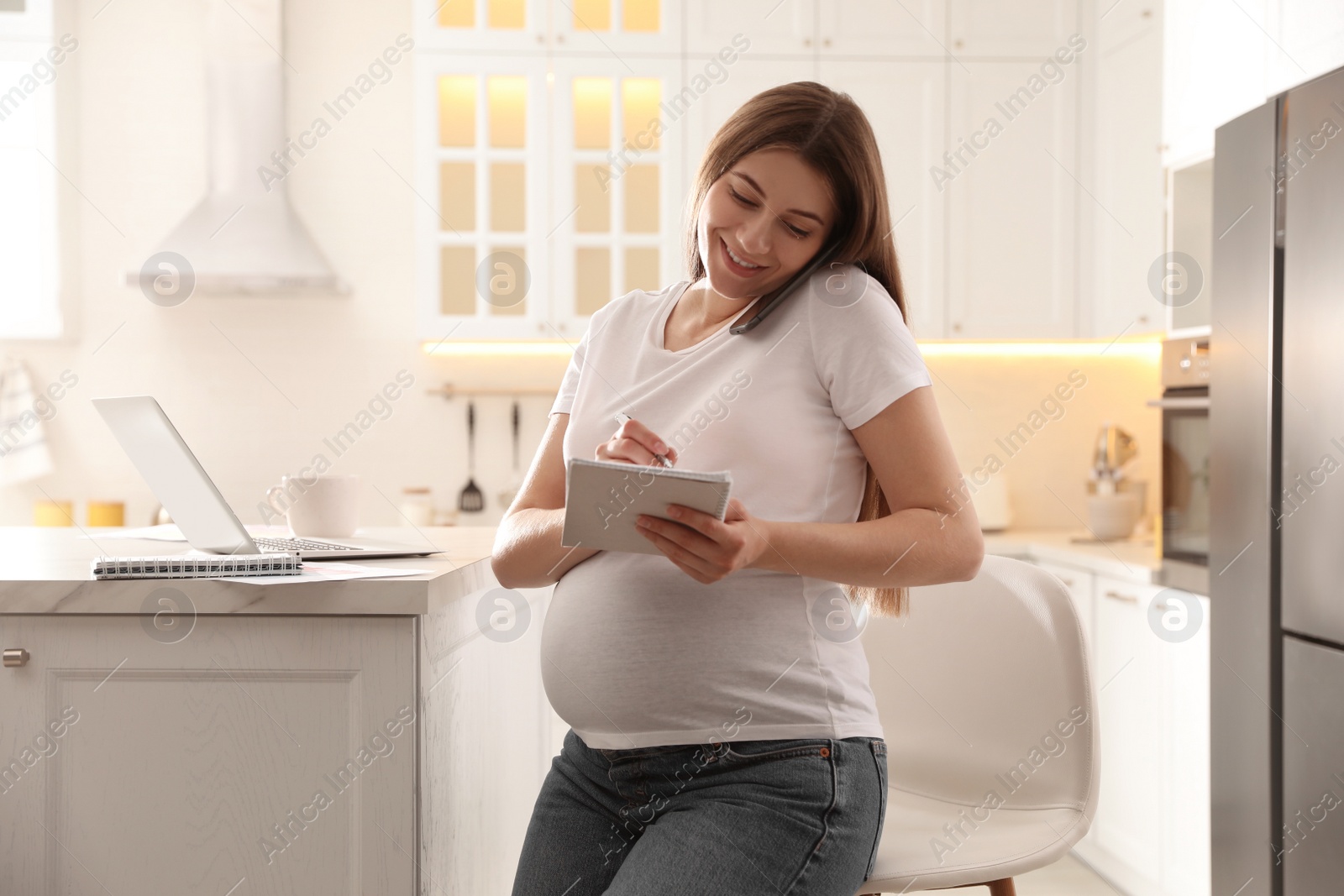 Photo of Pregnant woman working in kitchen at home. Maternity leave