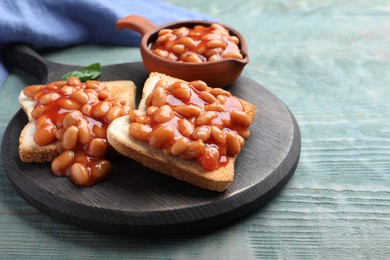 Photo of Toasts with delicious canned beans on light blue wooden table