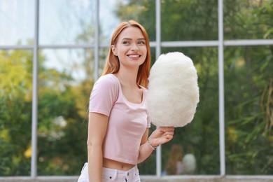 Smiling woman with white cotton candy outdoors