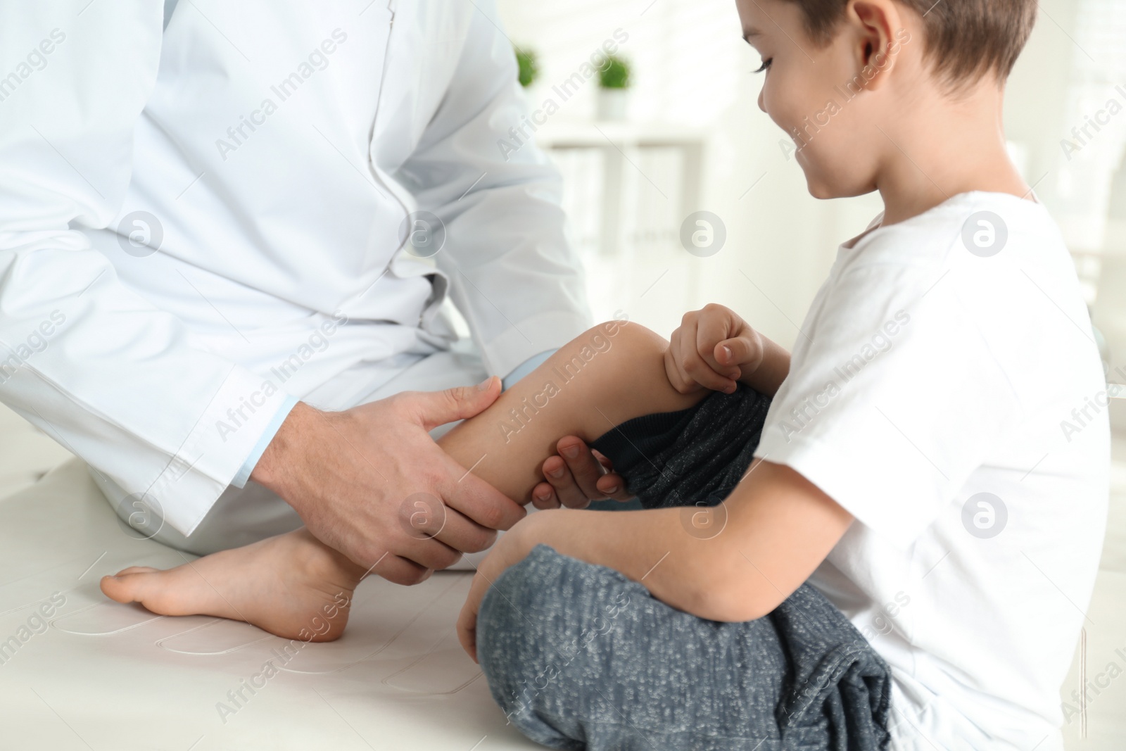 Photo of Professional orthopedist examining little patient's leg in clinic