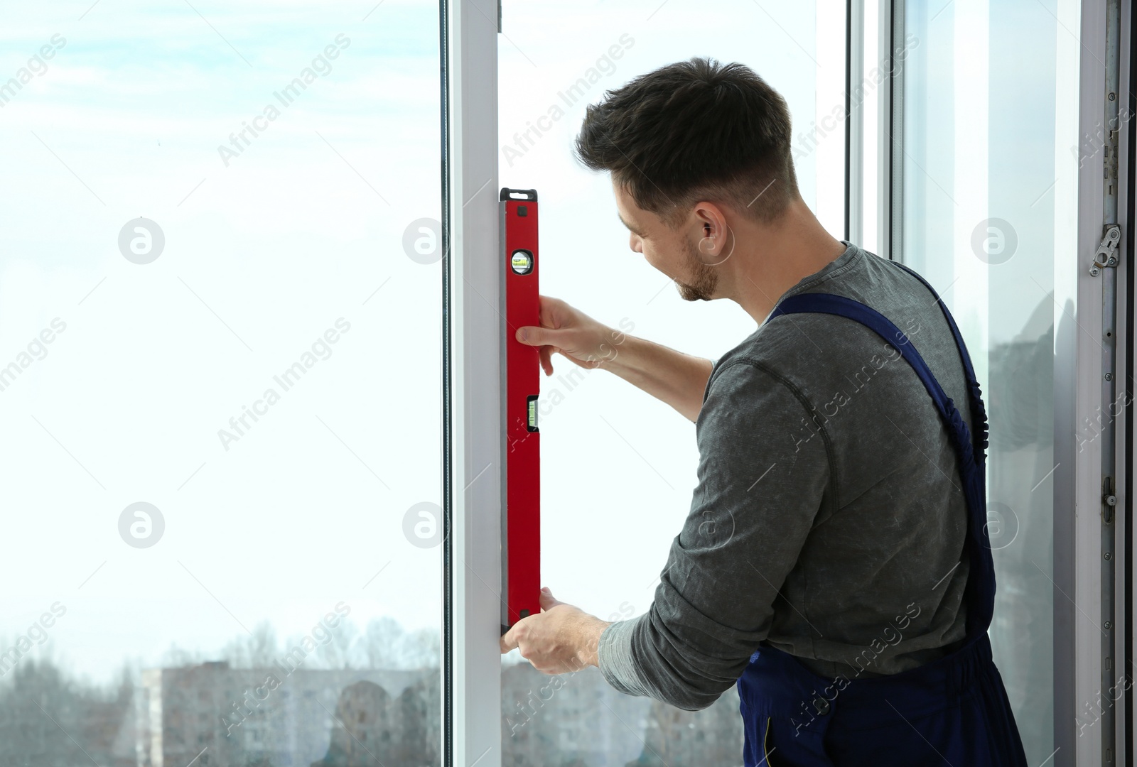 Photo of Construction worker using bubble level while installing window indoors