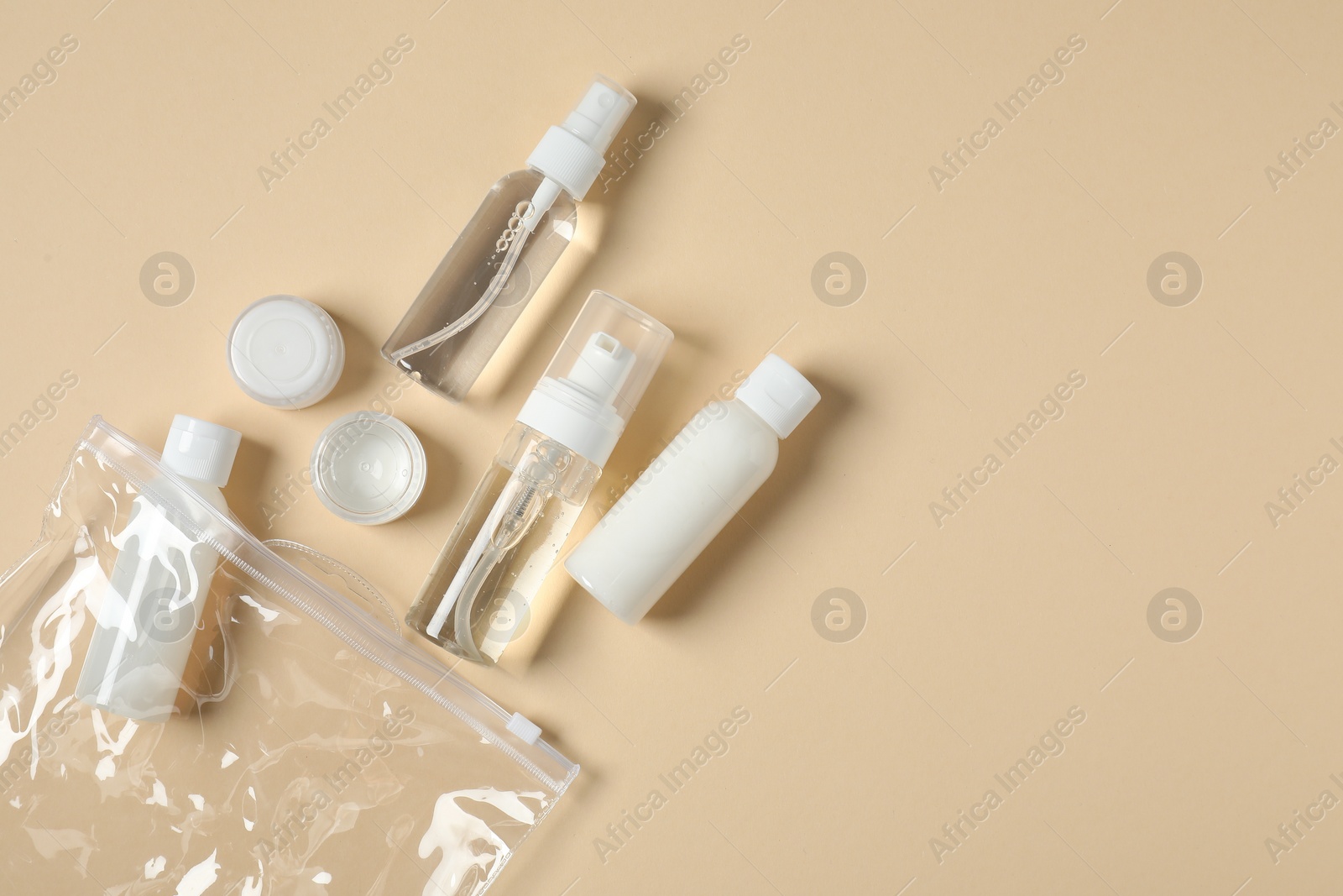 Photo of Cosmetic travel kit and plastic bag on beige background, flat lay with space for text. Bath accessories