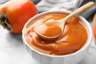 Delicious persimmon jam and fresh fruits on table, closeup