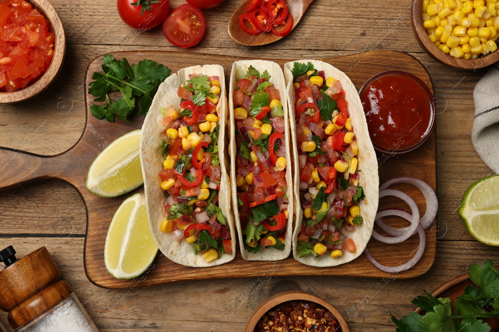 Photo of Tasty tacos with vegetables on wooden table, flat lay