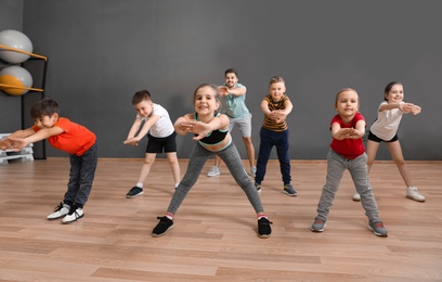 Cute little children and trainer doing physical exercise in school gym. Healthy lifestyle