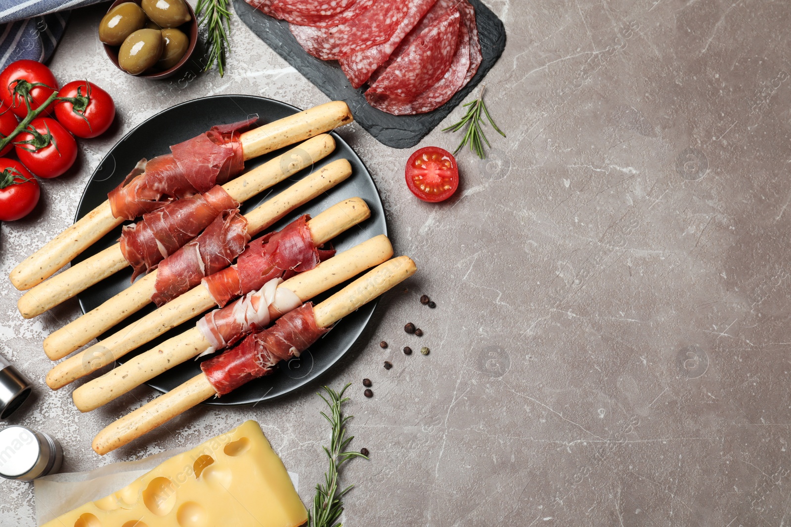 Photo of Tasty prosciutto served on brown marble table, flat lay. Space for text