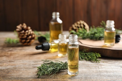 Composition with bottle of conifer essential oil on wooden table. Space for text