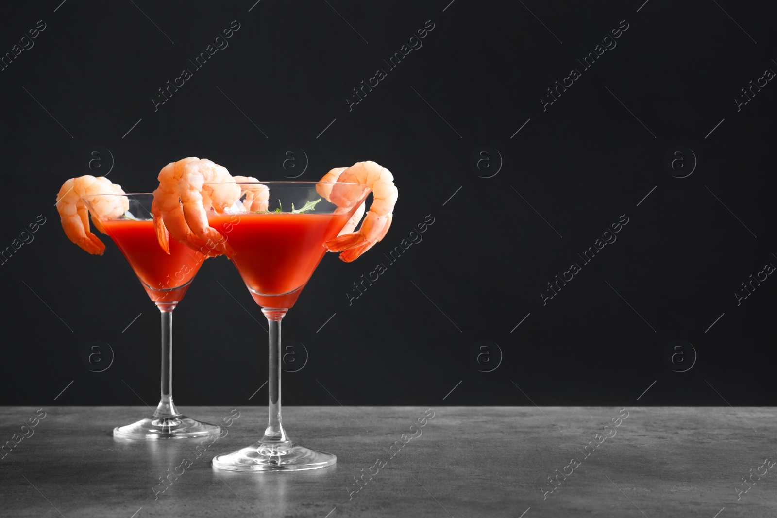 Photo of Glasses with boiled shrimps and tomato sauce on table