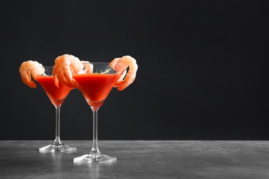 Photo of Glasses with boiled shrimps and tomato sauce on table