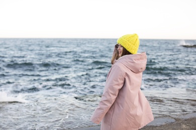 Young woman in warm clothes time near sea