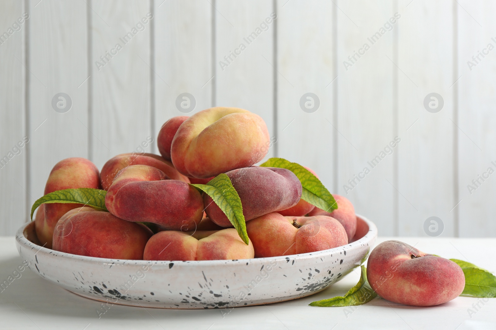 Photo of Fresh ripe donut peaches on white wooden table