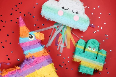Photo of Different bright pinatas on red background, flat lay