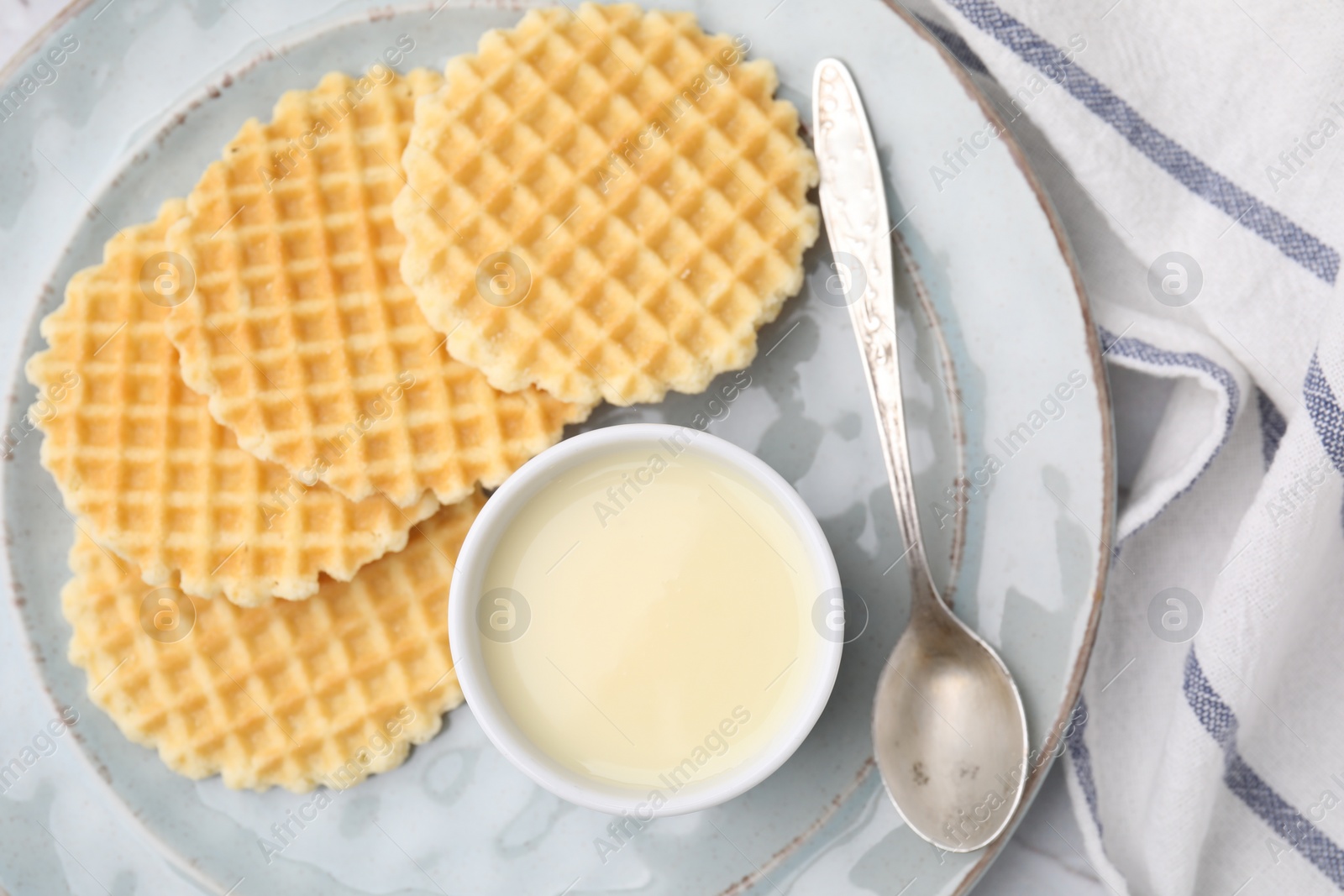 Photo of Tasty waffles served with condensed milk on table, top view