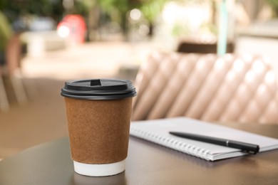 Photo of Paper cup of aromatic coffee on wooden table outdoors
