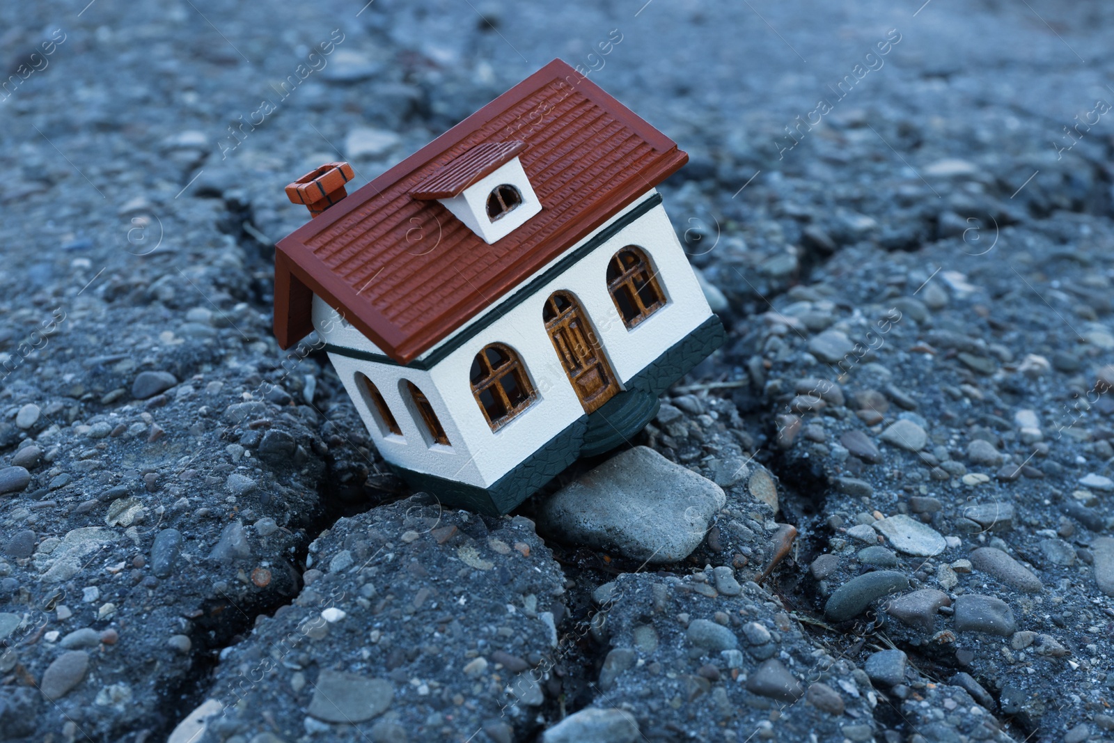 Photo of House model in cracked asphalt. Earthquake disaster