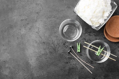 Glass containers, wicks and wax flakes on grey table, flat lay with space for text. Making homemade candles