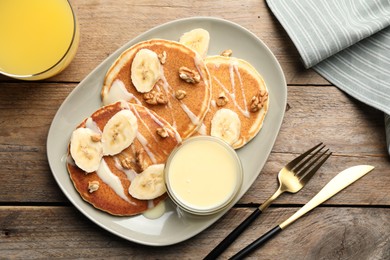 Photo of Tasty pancakes with sliced banana served on wooden table, flat lay