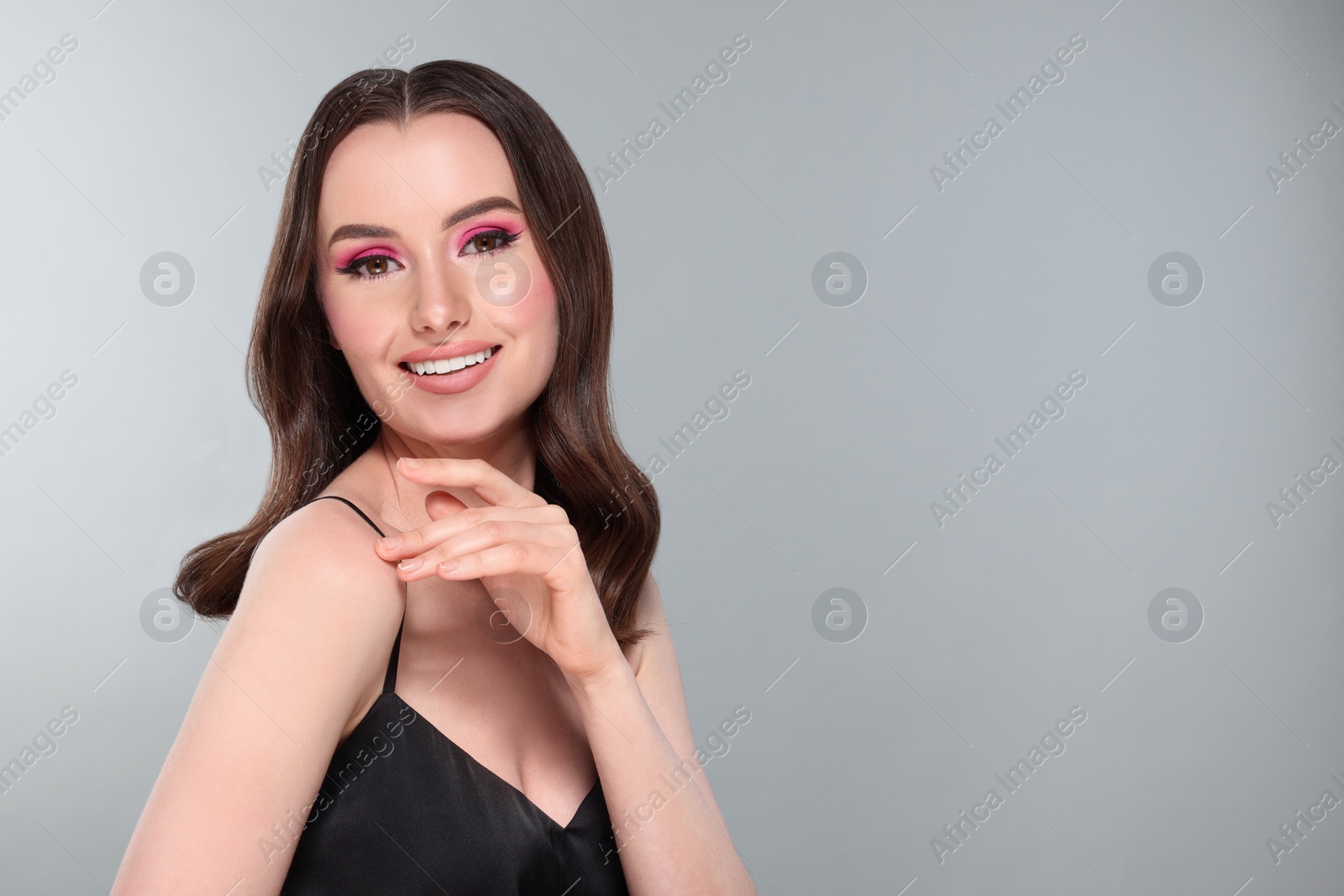 Photo of Portrait of beautiful young woman with makeup and gorgeous hair styling on light grey background. Space for text