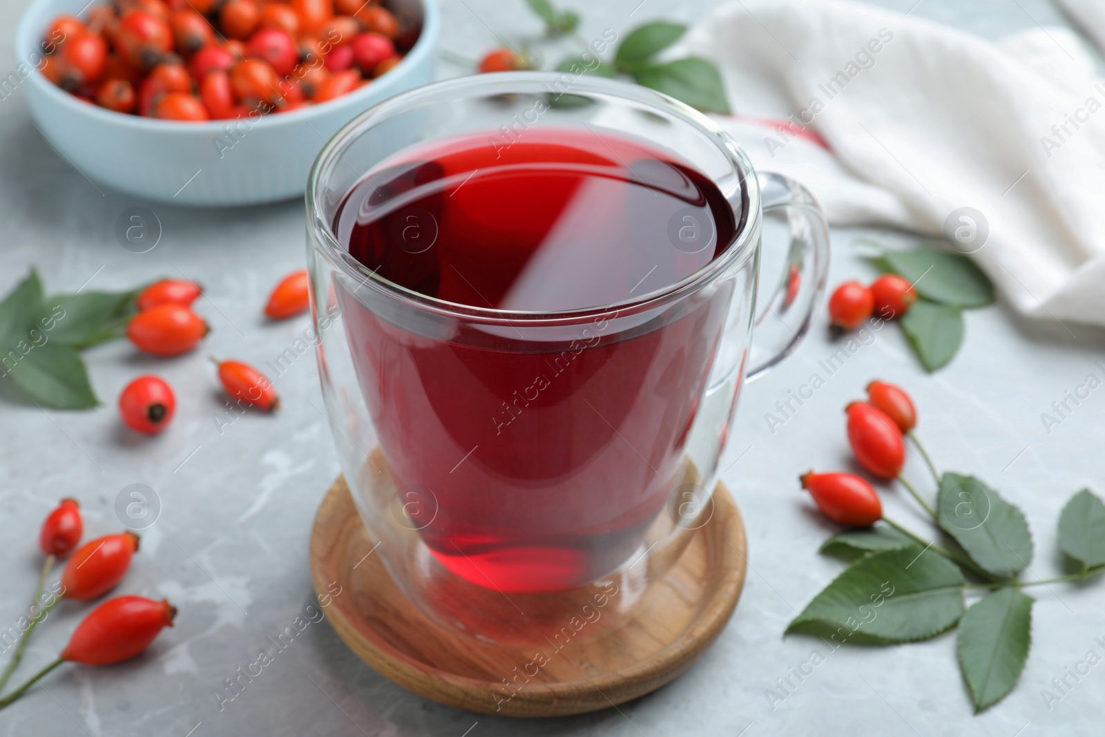 Photo of Aromatic rose hip tea and fresh berries on light grey marble table, closeup