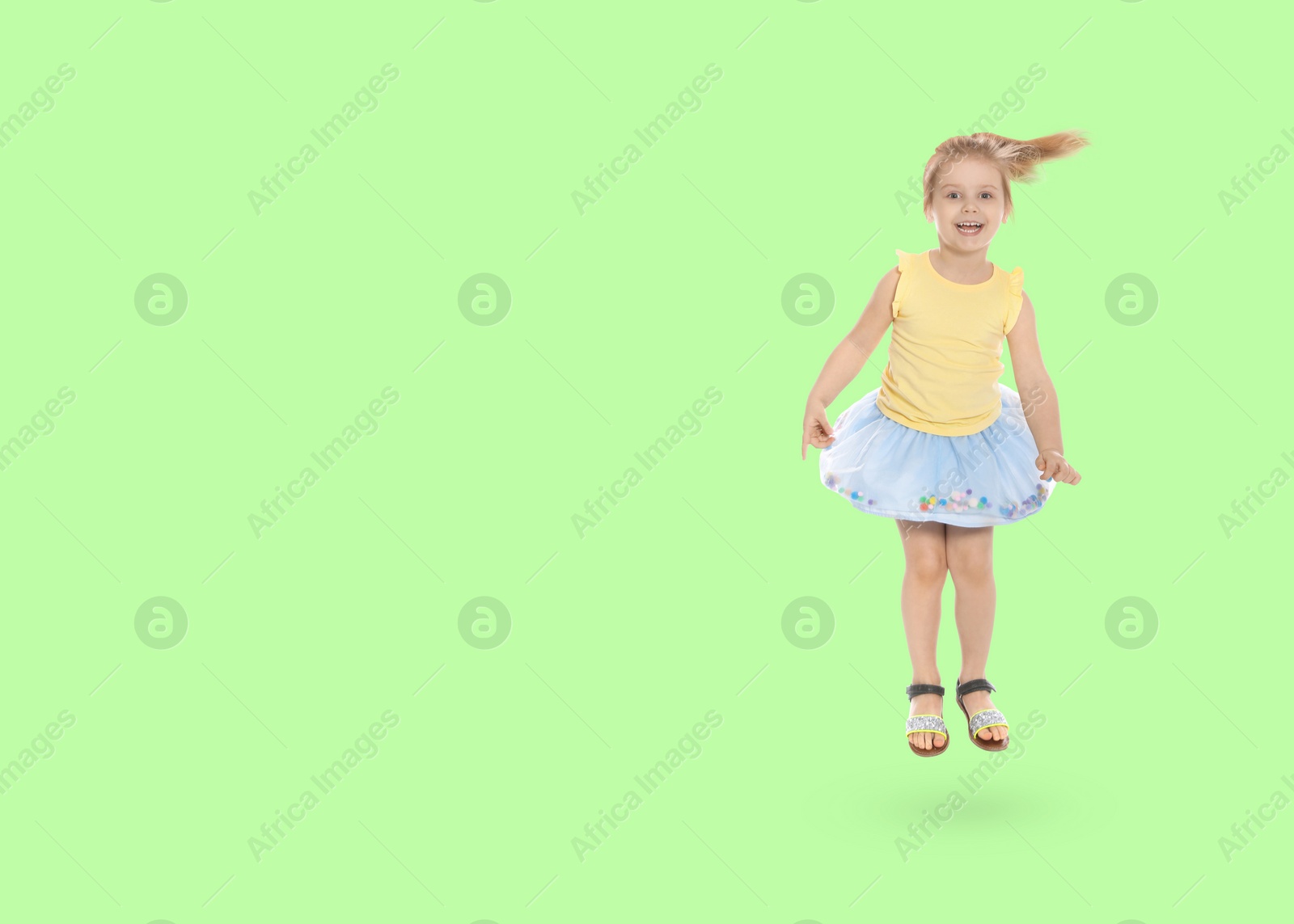 Image of Cute girl jumping on light green background, space for text