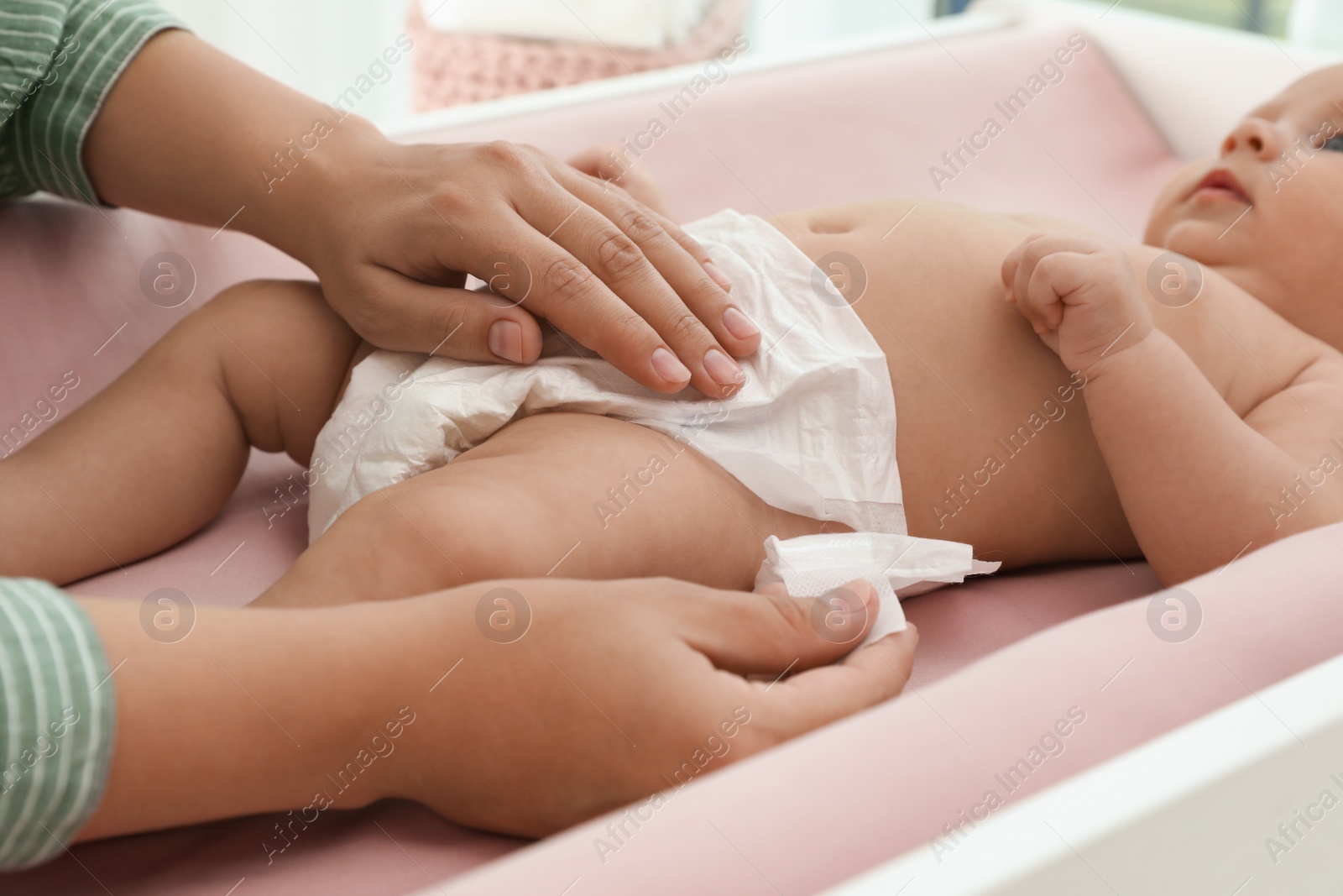 Photo of Mother changing her baby's diaper on table at home, closeup