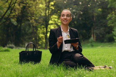 Photo of Lunch time. Happy businesswoman with container of salad on green grass in park