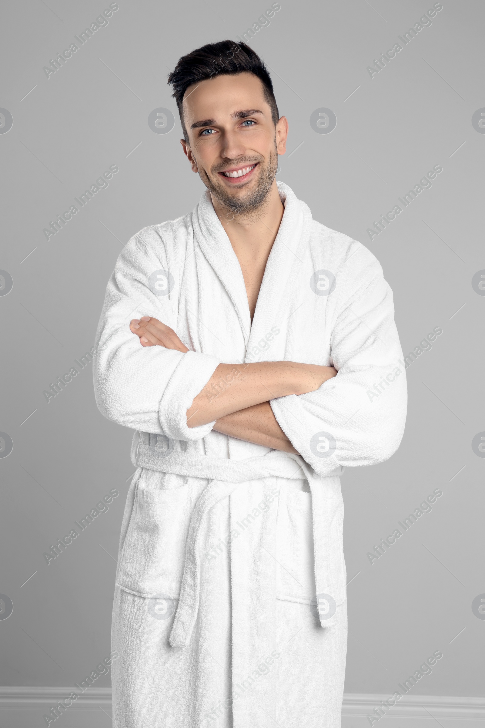 Photo of Happy young man in bathrobe on light grey background