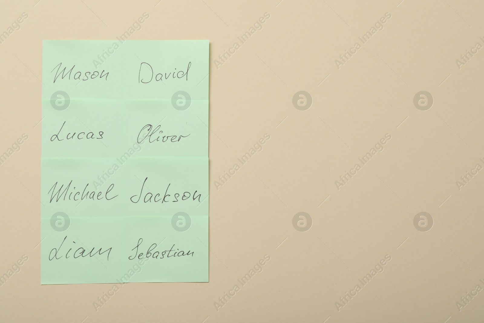 Photo of Choosing baby's name. Paper stickers with different names on beige background, top view. Space for text